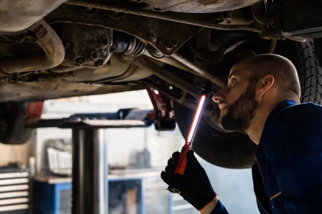 Mecánico trabajando bajo un vehículo elevado en un taller